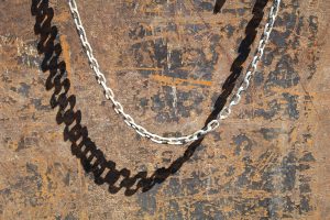 Chain and shadow against rusted metal at construction site in Houston, Texas